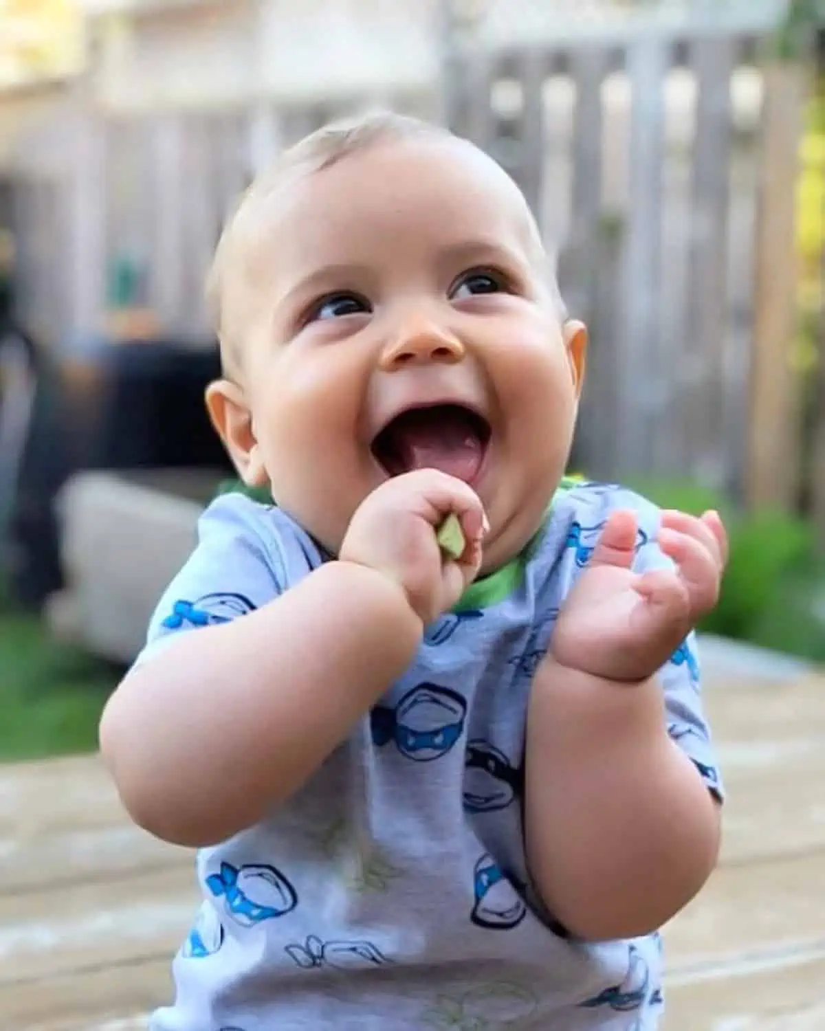 Image of a smiling 12 month old eating a cucumber for a post on dinner ideas for a 12 month old.