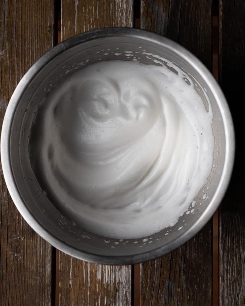 whipped aquafaba in a bowl on a wooden table