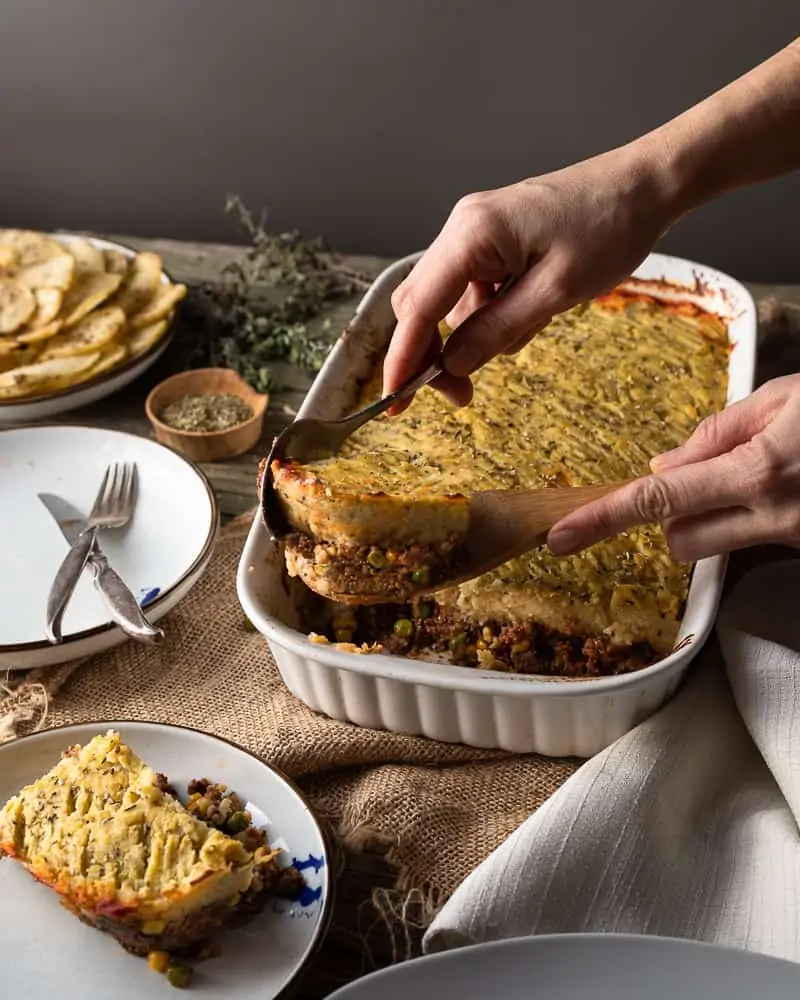 45 angle shot of vegan shepherds pie being served on a wooden dinner table