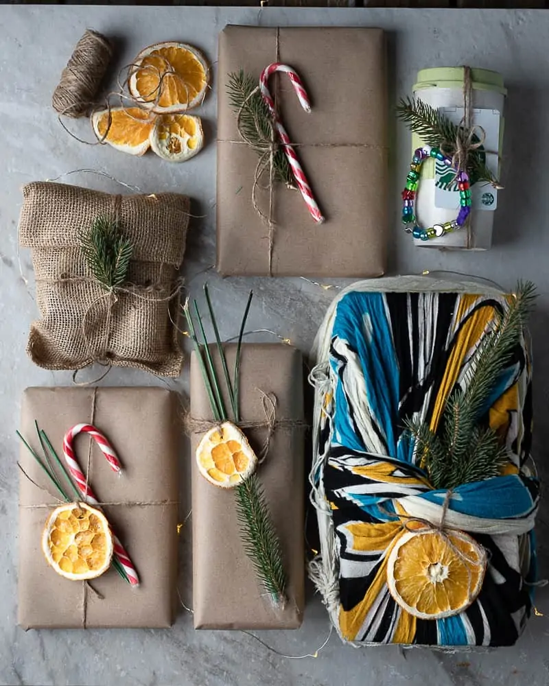 Eco-friendly wrapped presents decorated with candy canes and dried fruit on a marble table