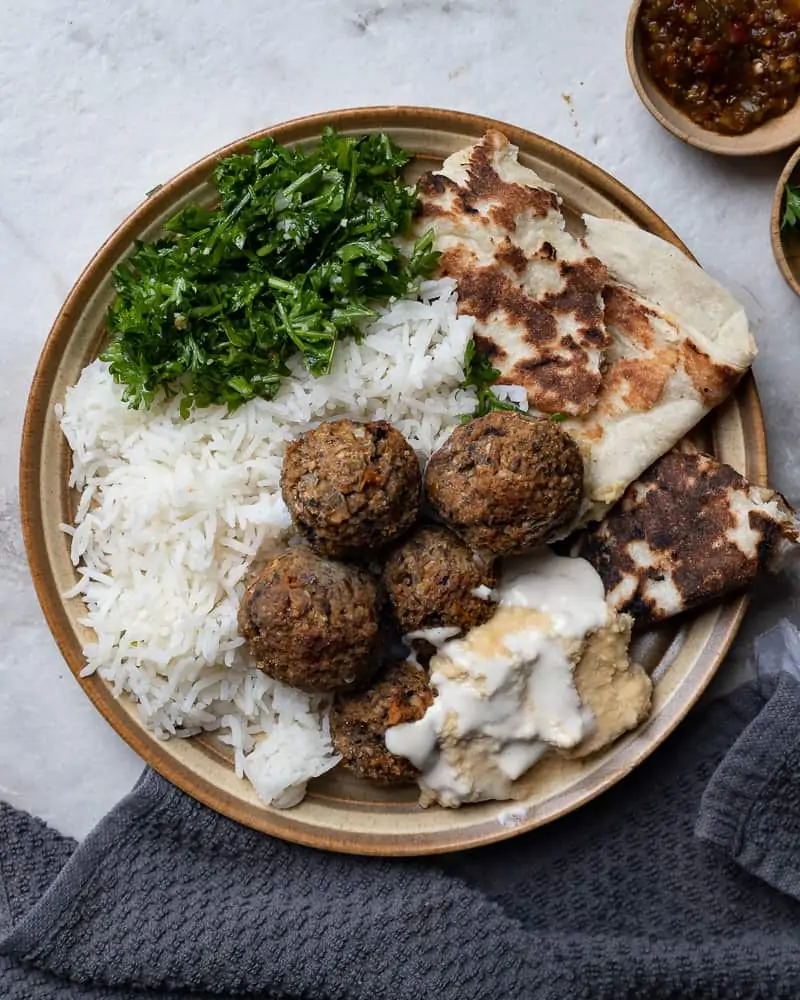 Plate with rice, pita bread meatballs and hummus on a marble table