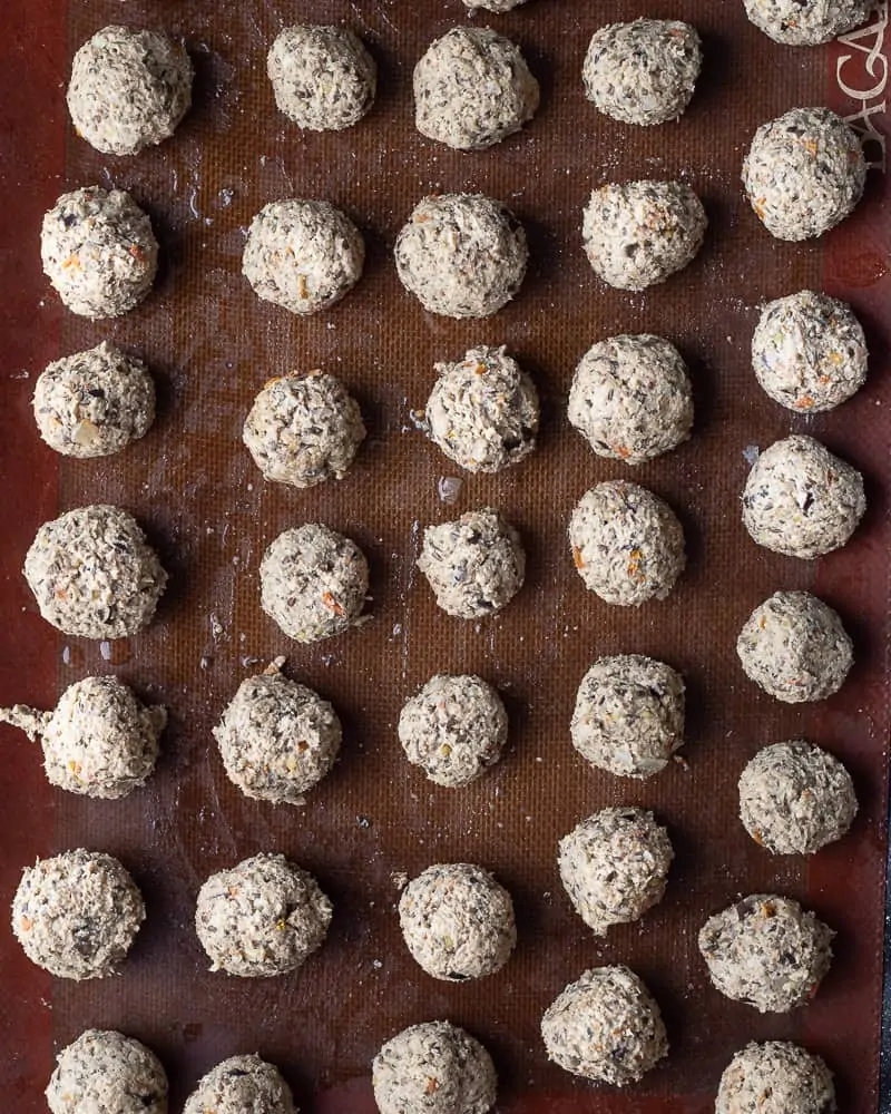 Top-down view of a baking pan with baked egg-free vegan eggplant meatball ready to be baked