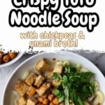 Overhead view of a bowl of tofu noodle soup topped with crispy tofu cubes, roasted chickpeas, chopped green onions, and fresh herbs in a light umami broth, served with gluten-free elbow pasta.