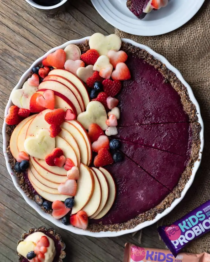 Top down view of a raw no bake berry pie with fresh sliced apples and strawberries on top
