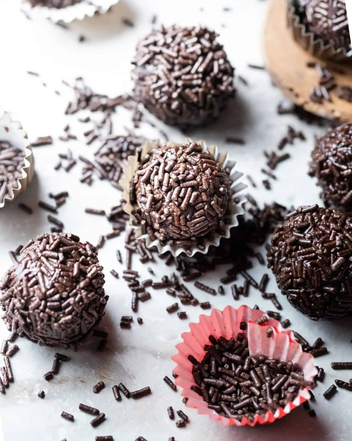 Vegan fudge balls in mini cupcake liners sitting on a countertop.