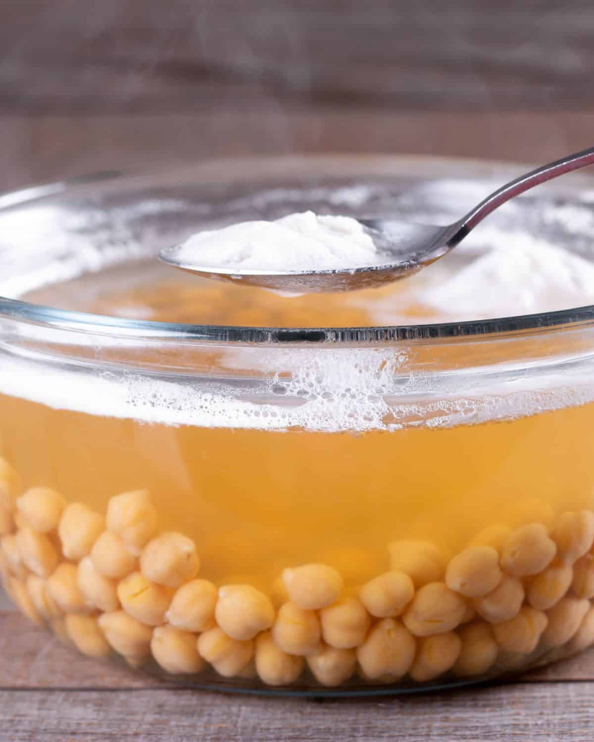Glass bowl of chickpeas and chickpea liquid to show what Aquafaba is. The image is for a recipe post on how to use aquafaba in place of eggs.