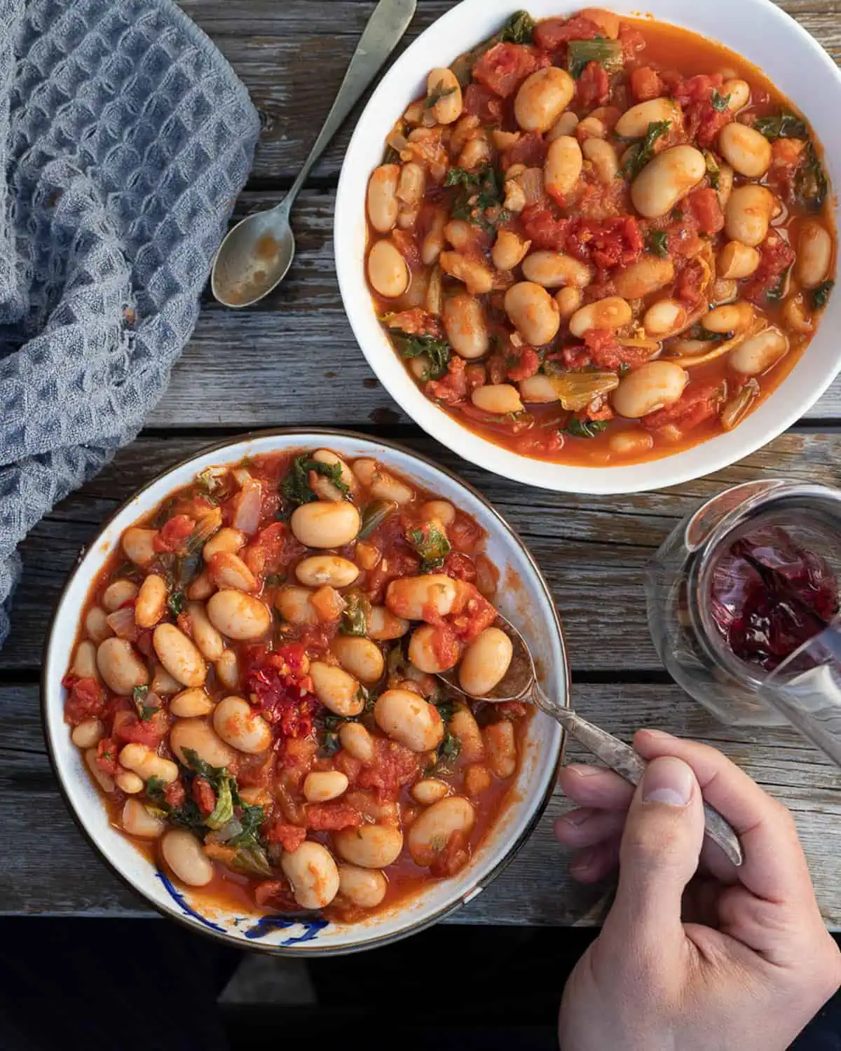 Image of two bowls of white bean stew being eatten on a picnic table.