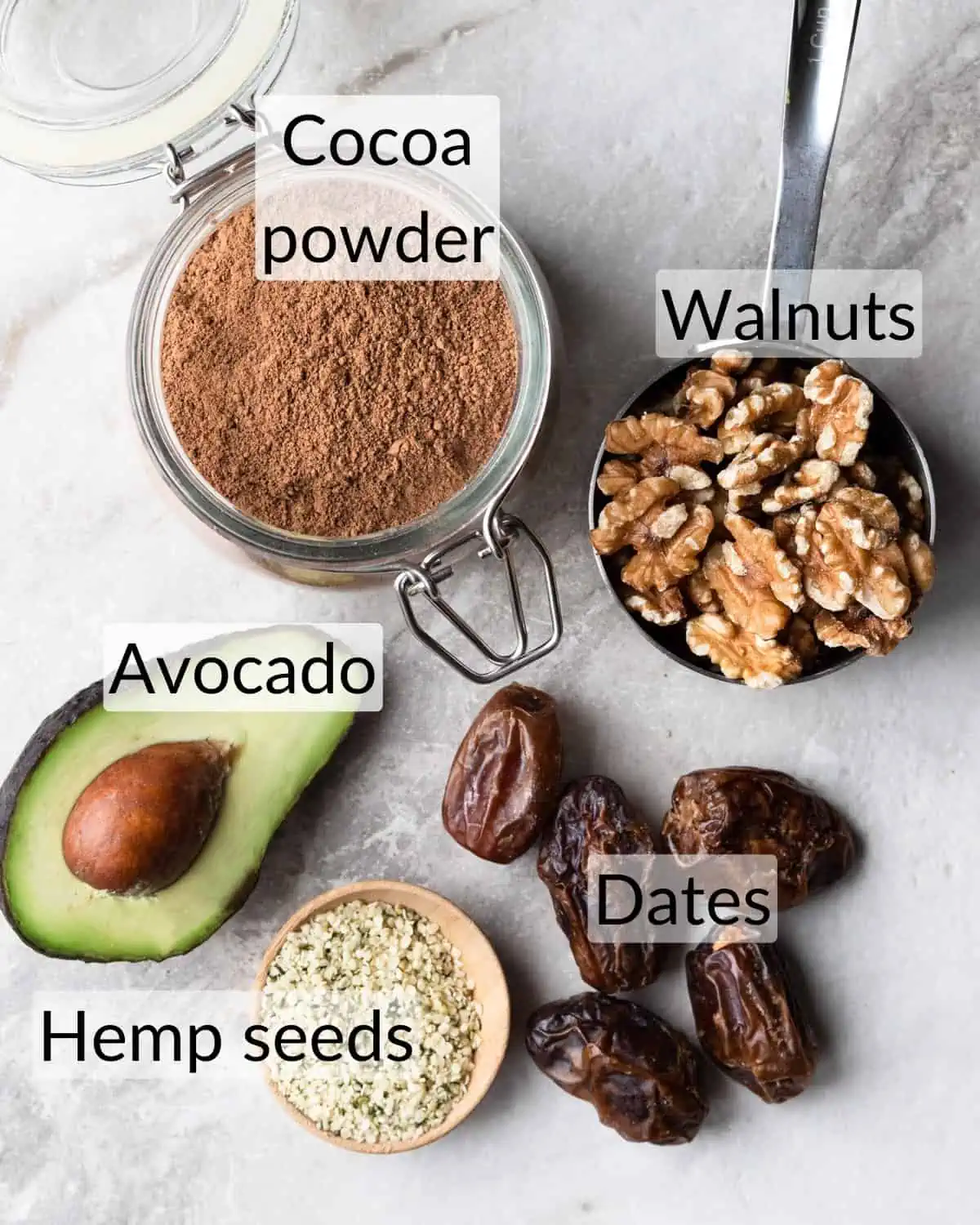 Ingredient shot of how to make healthy bliss balls. The recipe includes dates, hemp seeds, walnuts, avocado and cocoa powder.