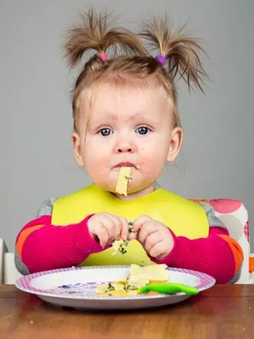 Image of a toddler enjoying a plate of pasta to show what a typical 12 month old eats in a day