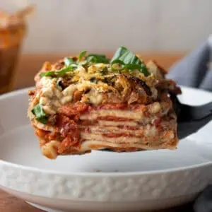 Close up image of gluten free vegan lasagna for a recipe post on how to make this easy weeknight recipe. The image shows the finished product with the layers of glute free noodles and homemade tomato lentil sauce and vegan cheese.