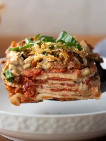 Close up image of gluten free vegan lasagna for a recipe post on how to make this easy weeknight recipe. The image shows the finished product with the layers of glute free noodles and homemade tomato lentil sauce and vegan cheese.