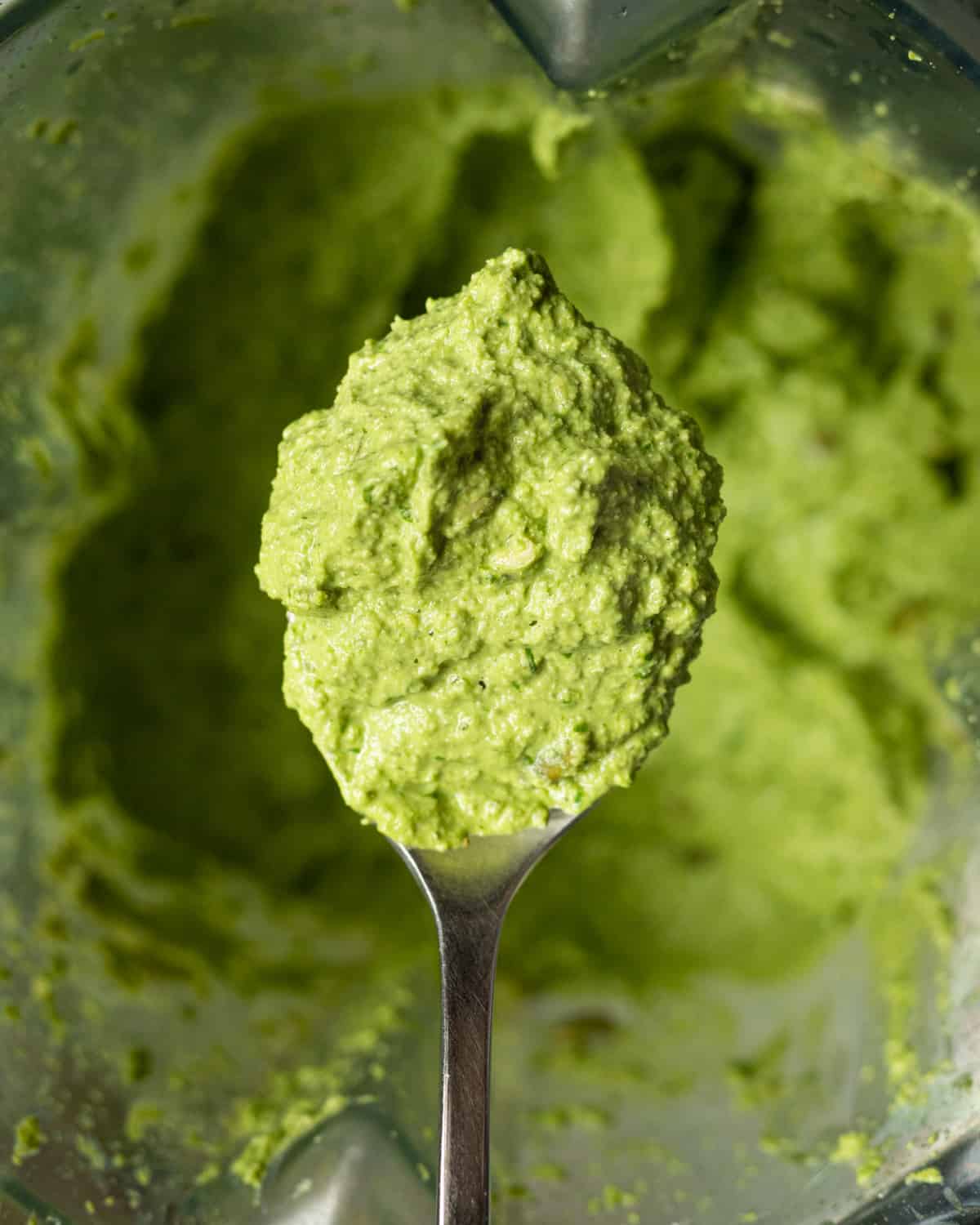 Close up image of a spoon of pesto sauce made without pine nuts to show the texture for the recipe post.