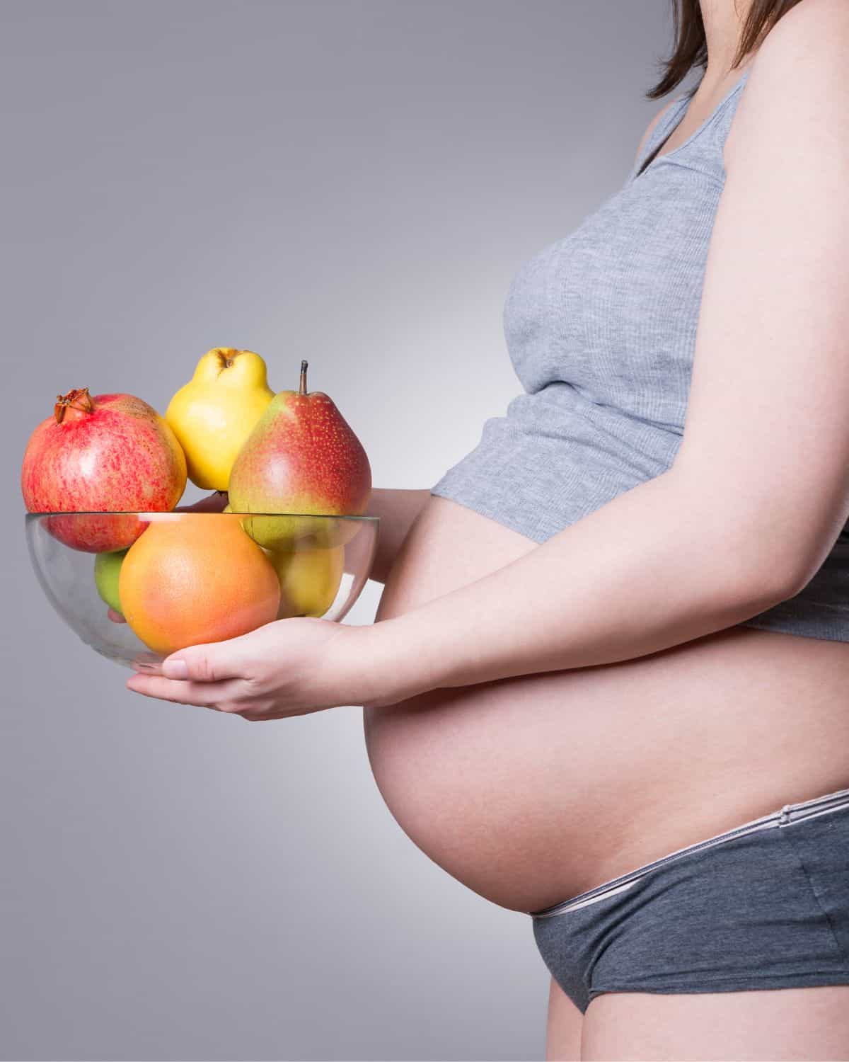 Image of a pregnant woman ensuring optimal nutrition with a plate full of plant-based food who is following a vegan pregnancy meal plan