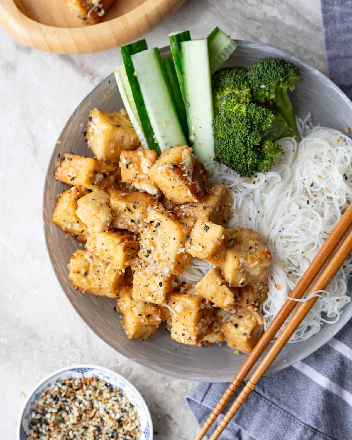 Image of a bowl of Chinese General Tso tofu with noddles and steamed brocolli.