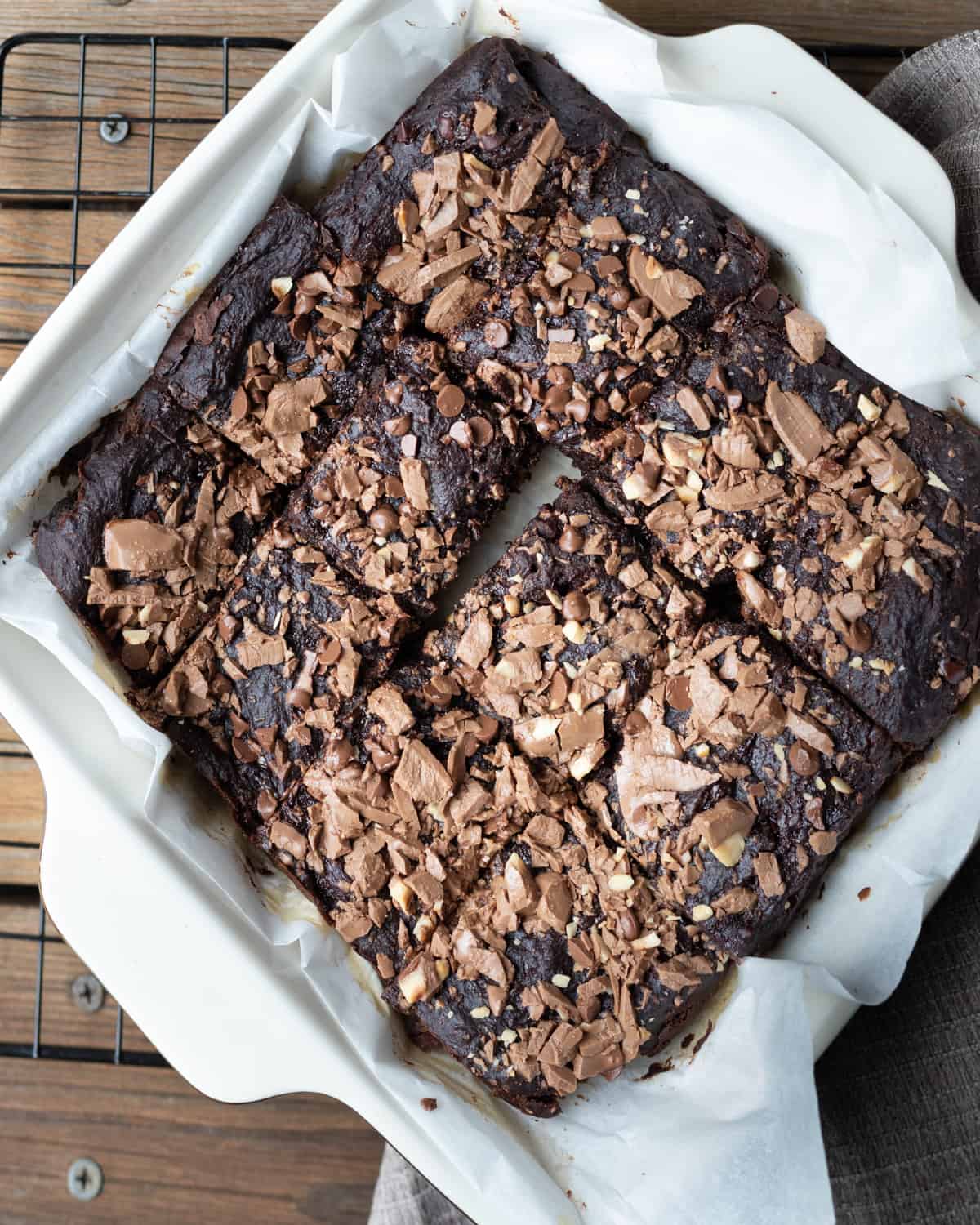 Cooked dairy-free brownies in a cake pan. The brownies are cut into squares and topped with chocolate chips.