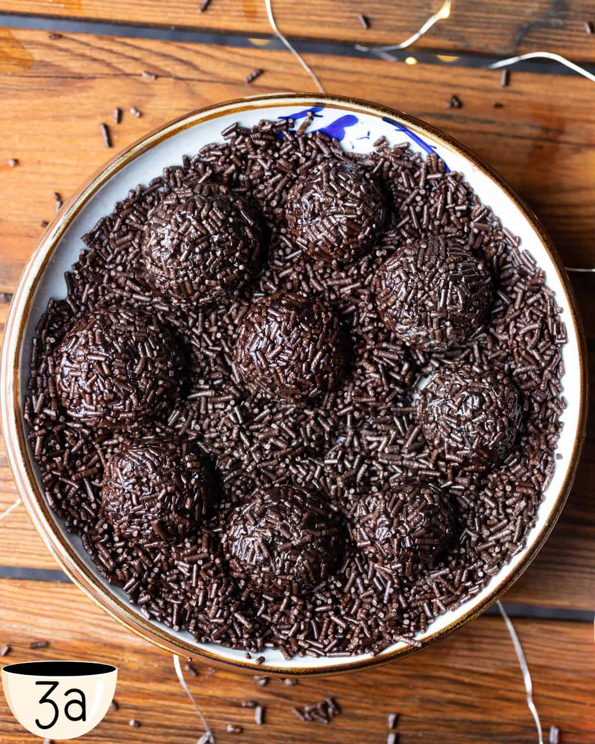 A plate full of choclate sprinkles with fudge balls placed in the plate ready to roll. 