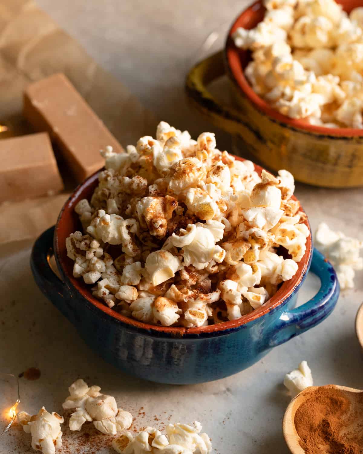 Close up image of a bowl of vegan cinnamon popcorn. The image is cozy and festive.