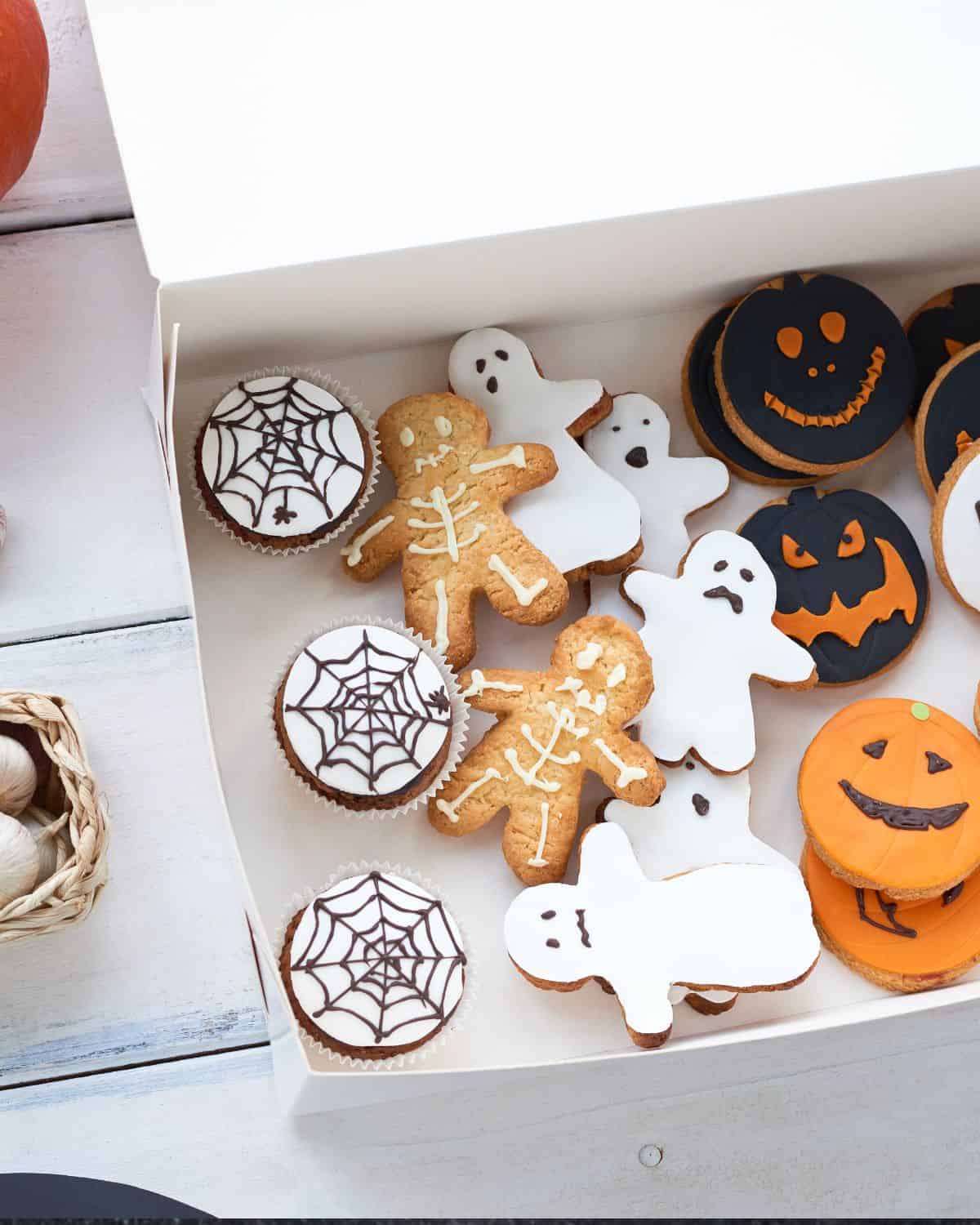 image of a box of halloween cookies decorted as ghosts, spider webs and pumpkins