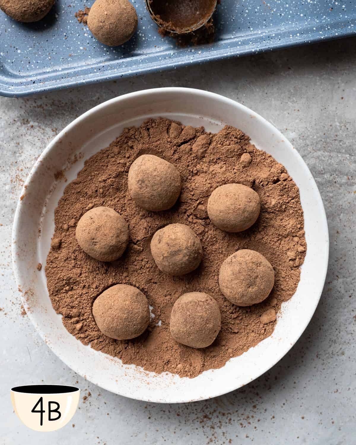 Several chocolate bliss balls for kids, covered in cocoa powder, sitting on a white dish with a light dusting of cocoa powder, showcasing the finished product.