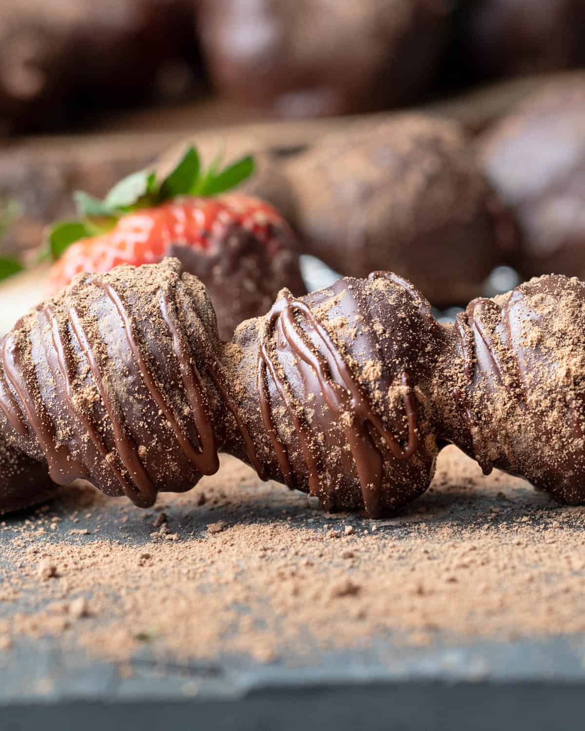Close up of fresh strawberries covered in chocolate and drizzled with cinnamon.