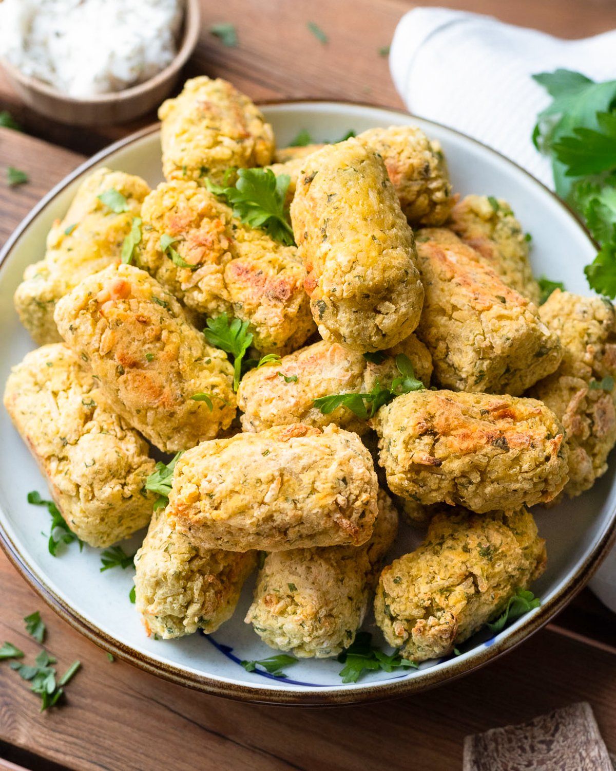 Baked rice balls sitting on a plate topped with fresh parsley. The texture is crispy and golden brown.