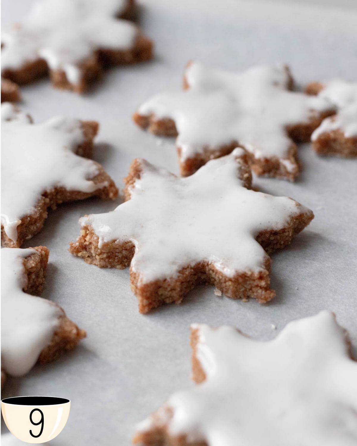 The finished vegan Zimtsterne cookies with a white glaze on top, freshly baked and set on parchment paper, displaying the classic appearance of this Swiss Christmas treat.