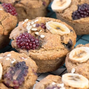 Gluten free blackberry muffins topped with fresh blackberries and banana slices, garnished with oat flakes.