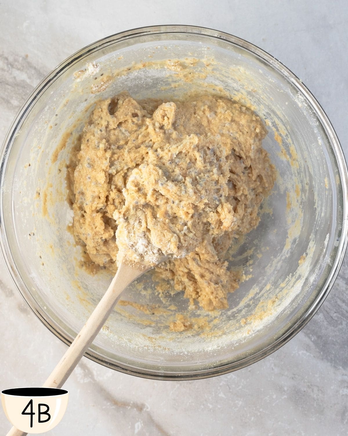 A glass bowl with a gluten free muffin batter being mixed together to show the consistency of the batter while prepping this recipe.