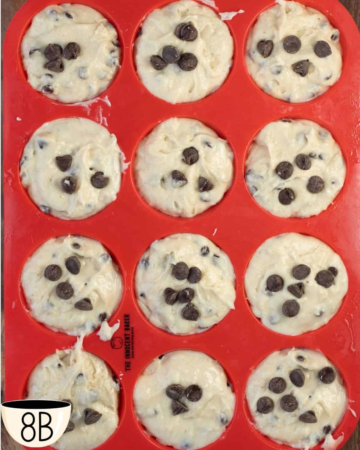 The silicone muffin tin filled with batter, now topped with a few extra chocolate chips on each muffin before baking.