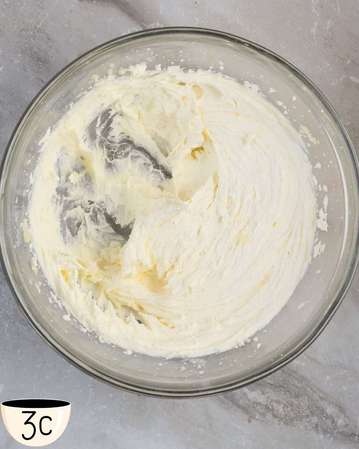 A settled mixture of whipped butter and sugar in a glass bowl ready for the next step in the recipe.