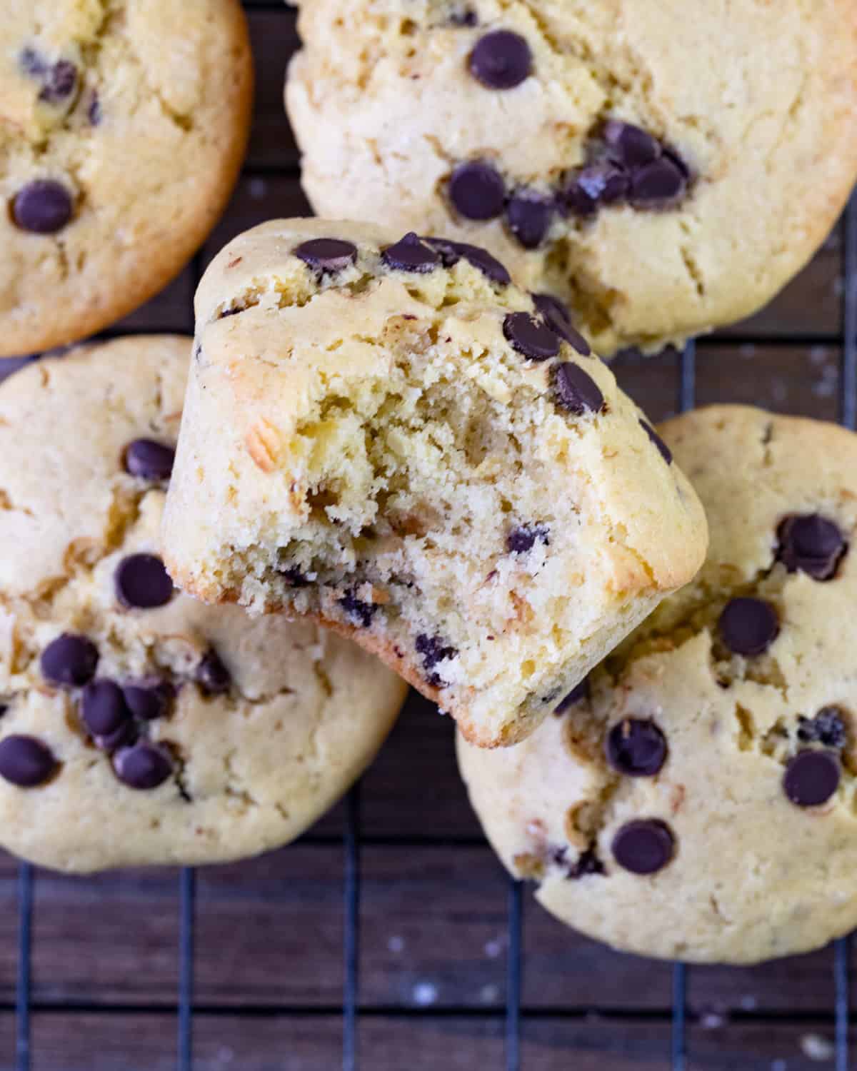 Overhead shot of a stack of gluten free muffins with a bite taken out of the center muffin showing the fluffy texture. 