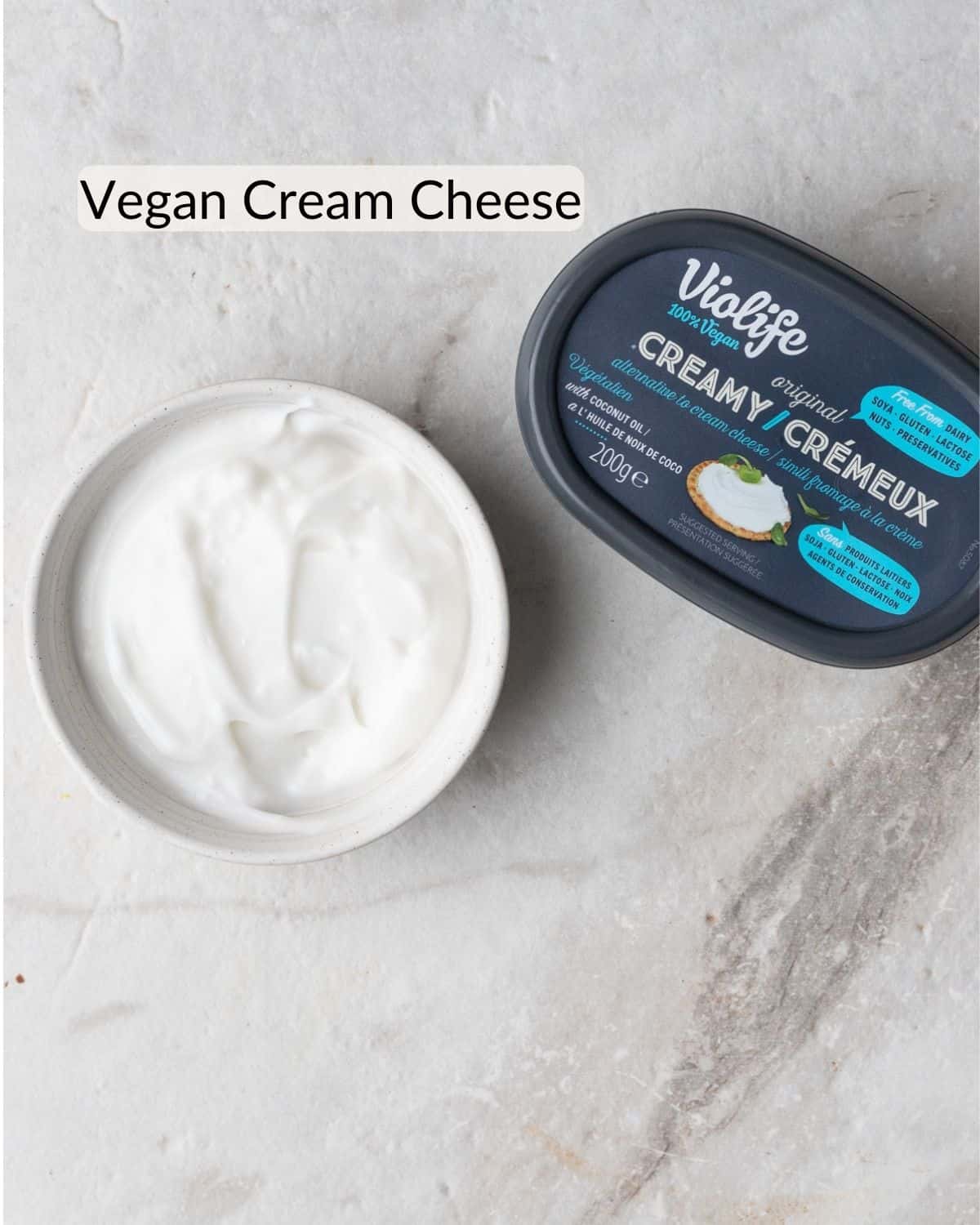 A bowl of vegan cream cheese next to its packaging, labeled 'Violife Creamy,' as a dairy-free alternative for making berry cheesecake overnight oats.