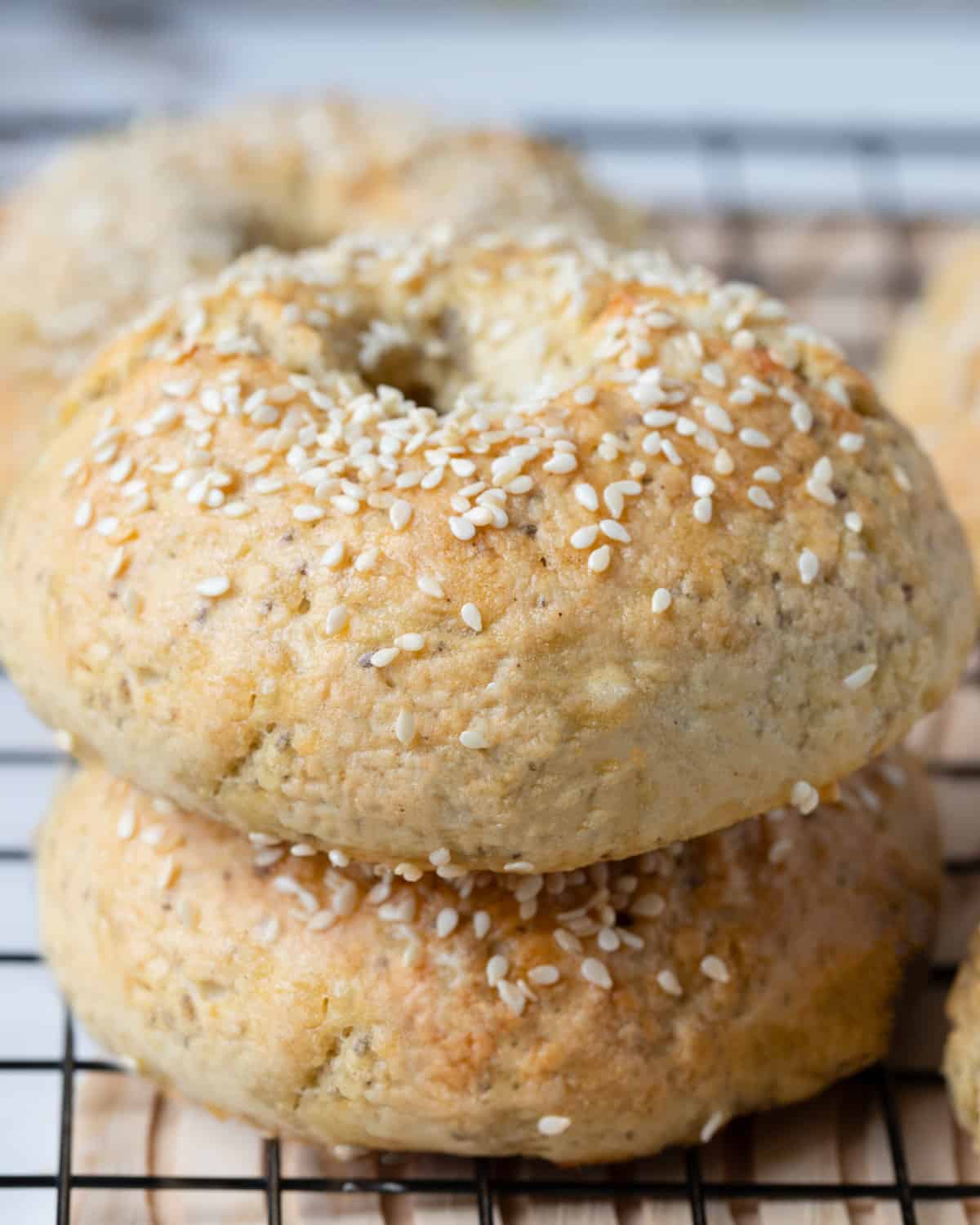 A closer view of the baked gluten-free vegan bagels with sesame seeds on a wire rack, showing the texture and color.