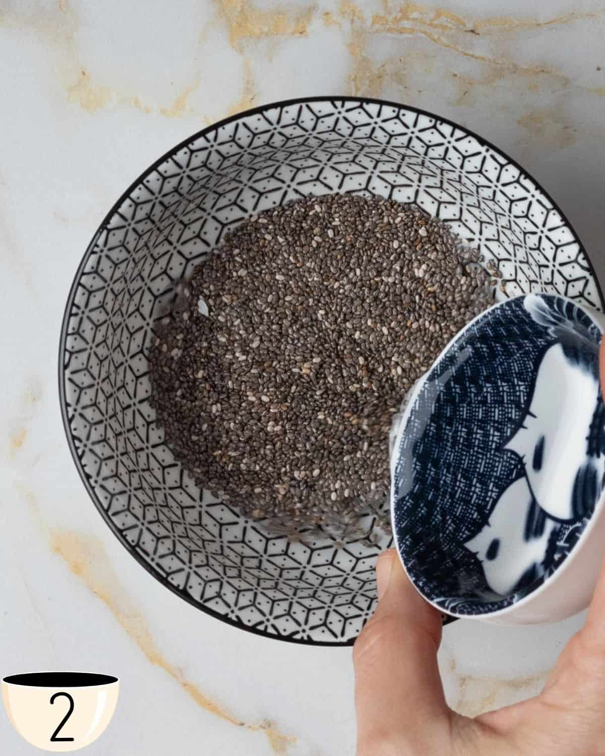 A small bowl of chia seeds before mixing, placed on a marble surface.