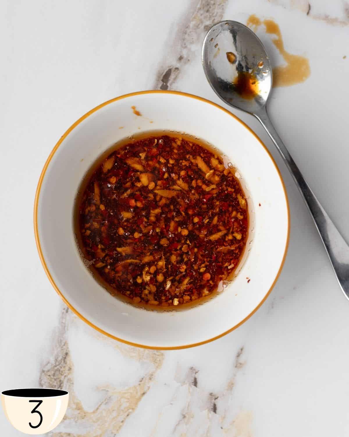 A bowl of spicy sauce mixture for noodle seasoning, with visible chili flakes and oil.