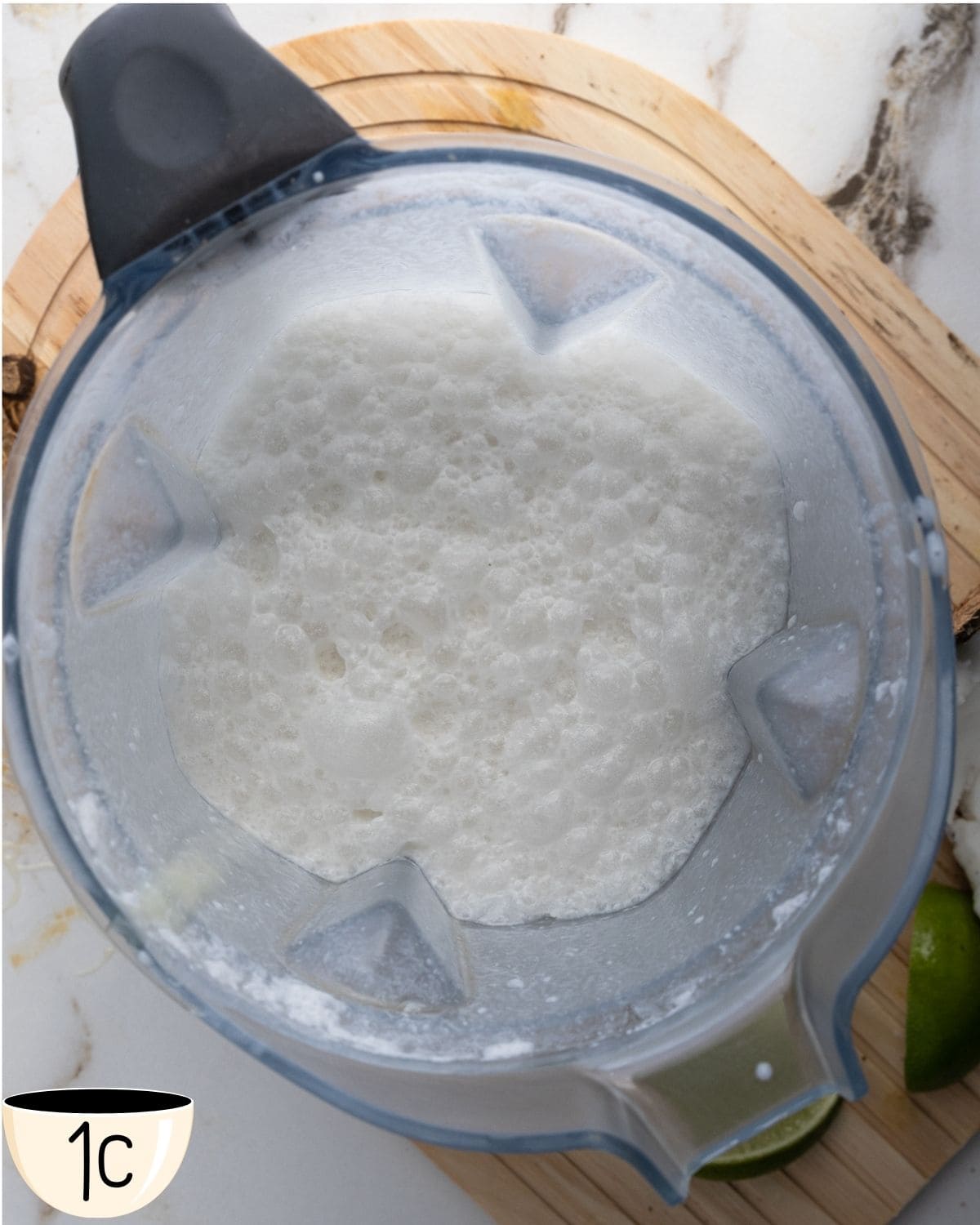Blender filled with a frothy mixture of coconut milk, condensed coconut milk, and lime juice.
