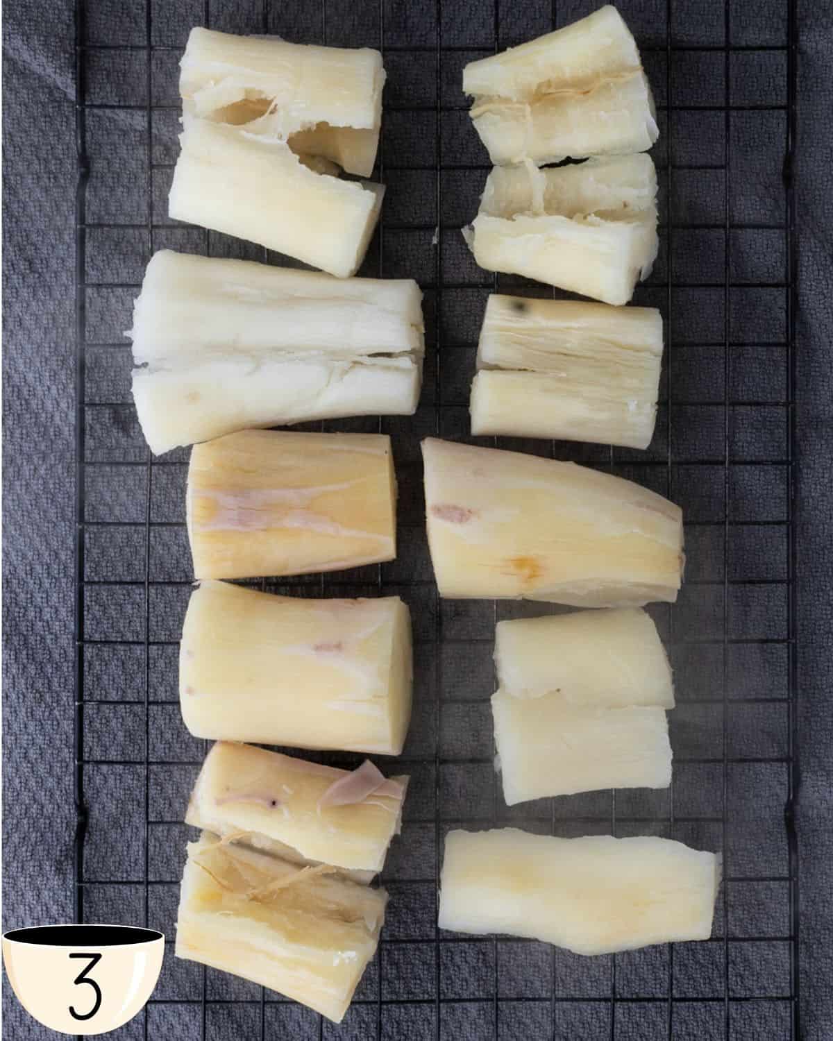 Boiled yuca pieces cooling on a wire rack to prevent them from becoming soggy.