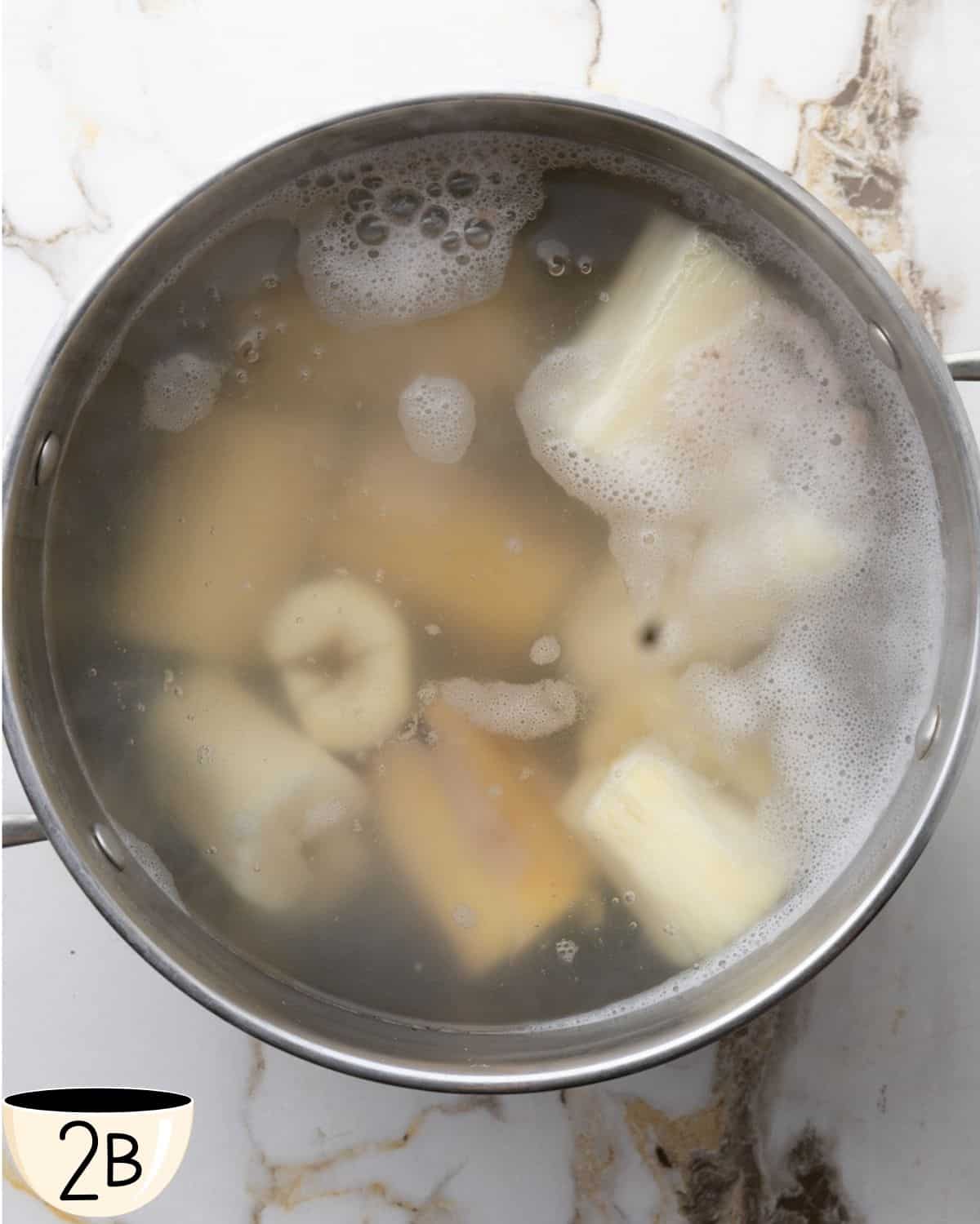 Yuca pieces boiling in a pot of water, starting to become tender and slightly translucent.