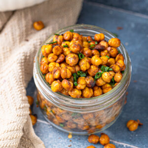 Glass jar filled with air-fried chickpeas seasoned with paprika, cumin, and green onion.