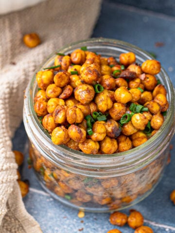 Glass jar filled with air-fried chickpeas seasoned with paprika, cumin, and green onion.