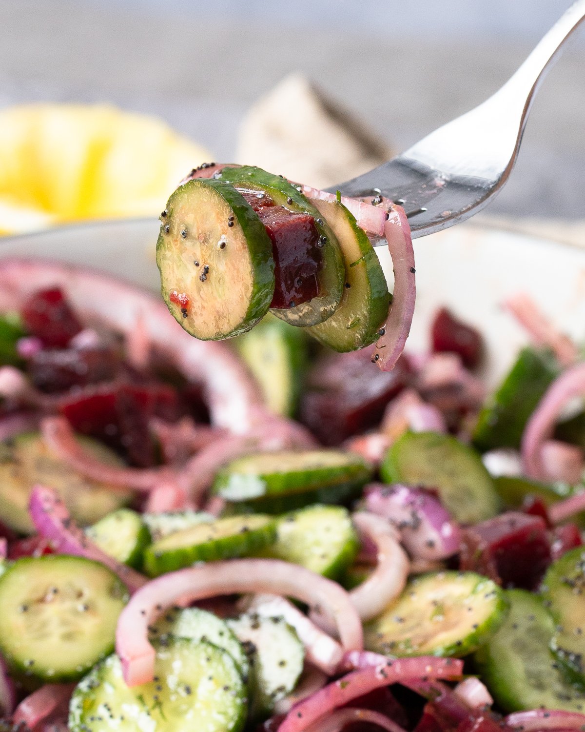 Fork holding a bite of cucumber, beet, and red onion from the finished salad.